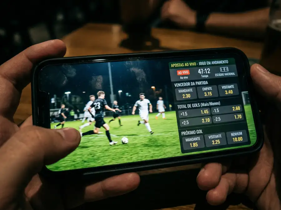 Telemóvel a transmitir jogo de futebol ao vivo em streaming com campo verde visível no ecrã