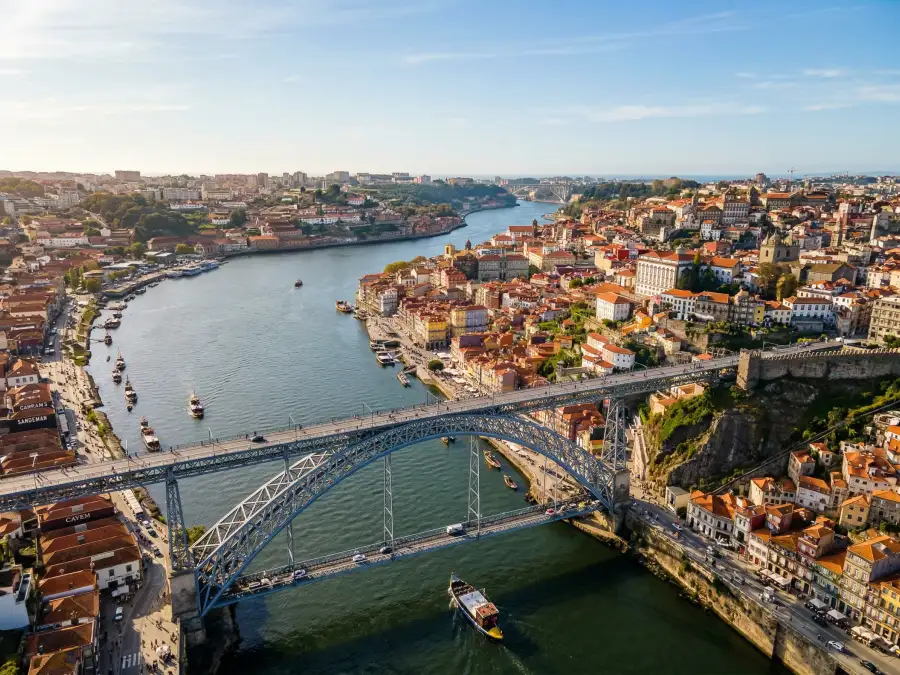 Vista aérea do Porto com o rio Douro e a ponte ao fundo numa tarde de sol