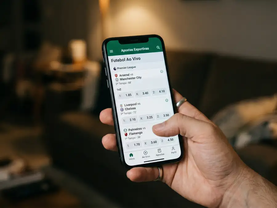 Ecrã de smartphone a mostrar interface de plataforma de apostas online com lista de odds desportivas